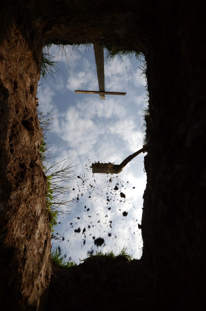 View upwards from the botom of a grave, a last glimpse of the sky. The gravedigger has begun covering the grave.
